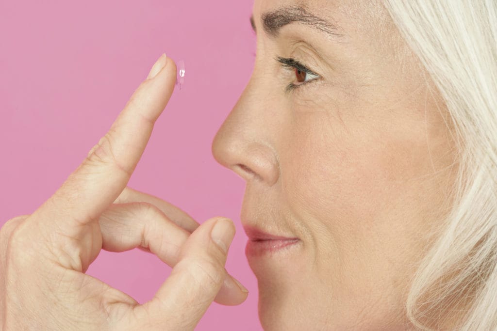mature woman inserting contact lens to illustrate