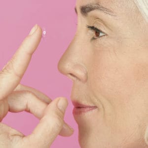 mature woman inserting contact lens to illustrate