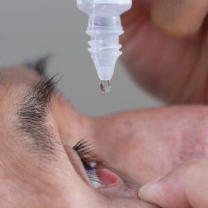A senior man uses eye drops