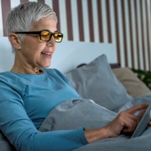 Senior lady wearing blue-light filter glasses looking at tablet